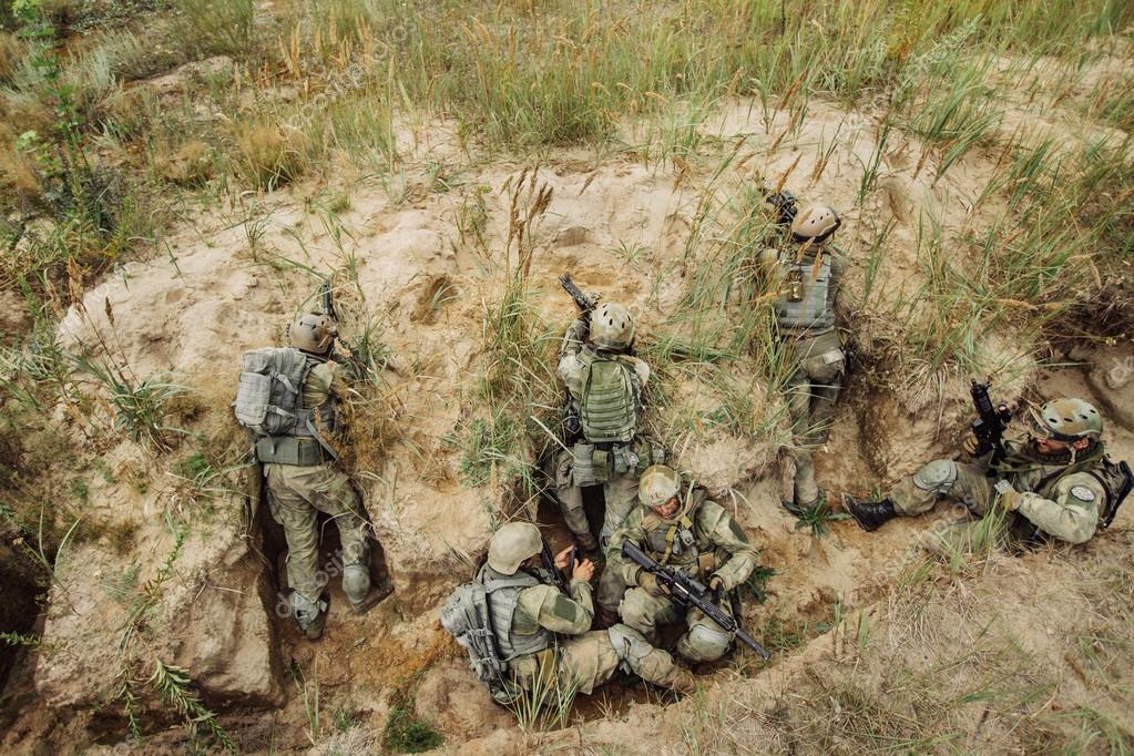 Group of soldiers hiding in the trenches and firing — Stock Photo