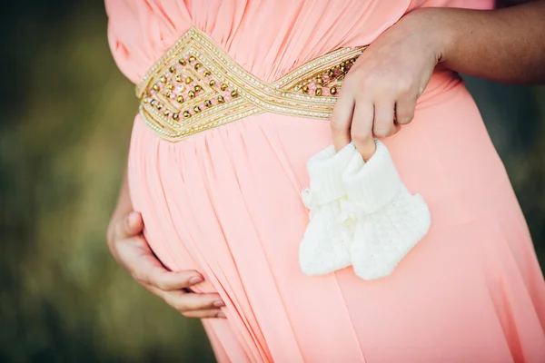 Pregnant woman holding baby booties — Stock Photo, Image