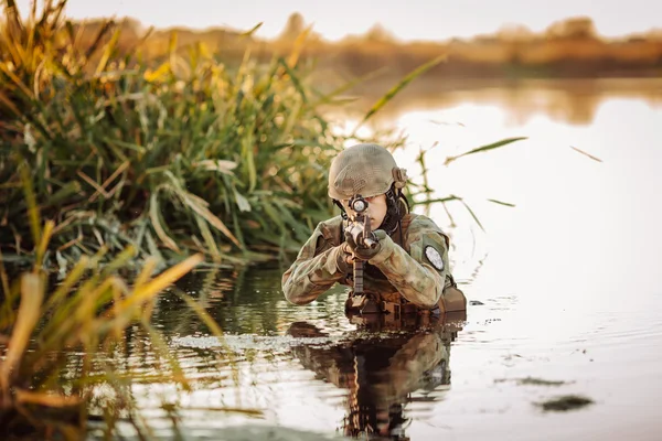 Soldato in movimento attraverso l'acqua e mirando al nemico — Foto Stock