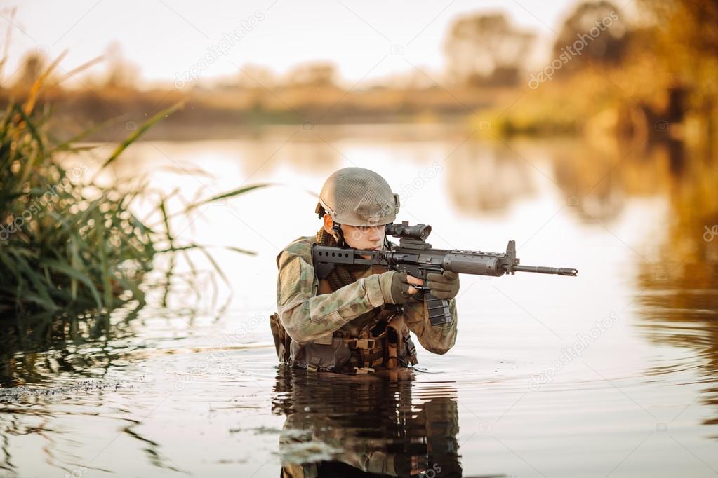 Soldier moving through the water and aiming at the enemy
