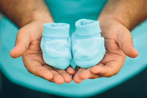 Man holding pair of baby shoes — Stock Photo, Image
