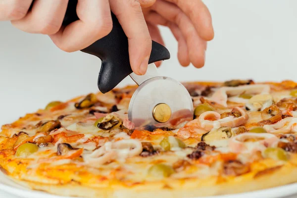 Pizza siendo cortada por el cortador — Foto de Stock