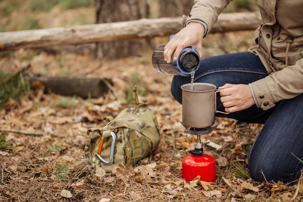 Mulher derrama água de uma garrafa em uma caneca — Fotografia de Stock