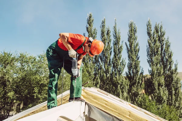 Dachdecker befestigt mit einem Bohrer eine Kappe auf einem Hausdach — Stockfoto