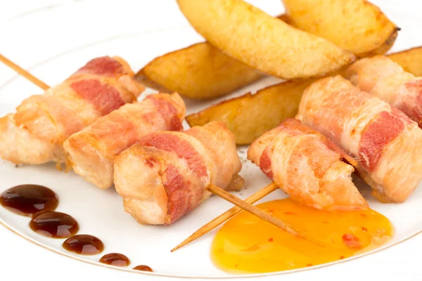 Thin rolls of bacon with slices of fried potatoes — Stock fotografie