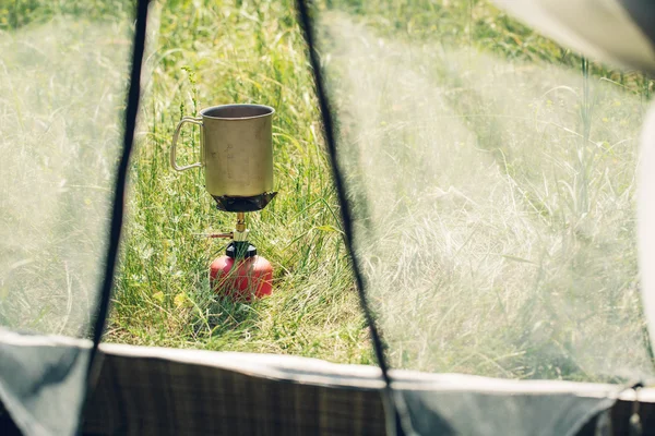 Agua hirviendo en taza en estufa de camping portátil — Foto de Stock