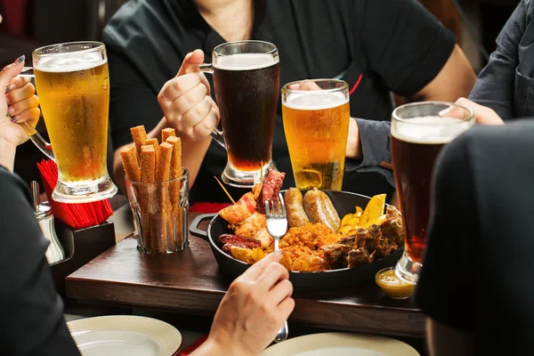 Hände halten Biergläser in der Kneipe — Stockfoto