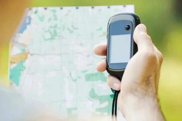 Homme tenant un récepteur GPS et un plan dans sa main . — Photo