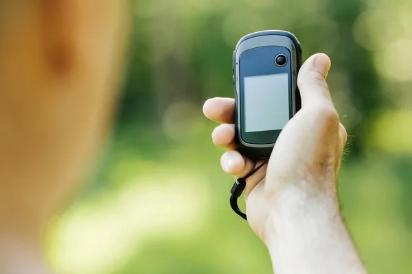 Hombre sosteniendo un receptor GPS y el plan en su mano . — Foto de Stock