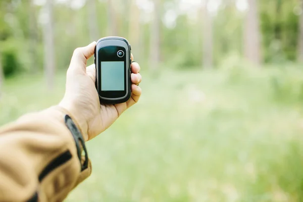 Hombre sosteniendo un receptor GPS y el plan en su mano . — Foto de Stock