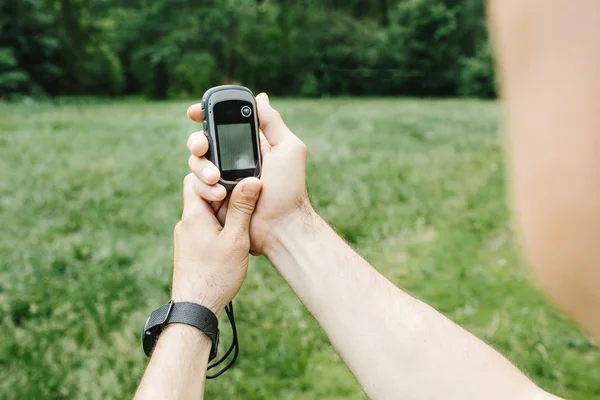 Man som innehar en GPS-mottagare och planerar i sin hand. — Stockfoto