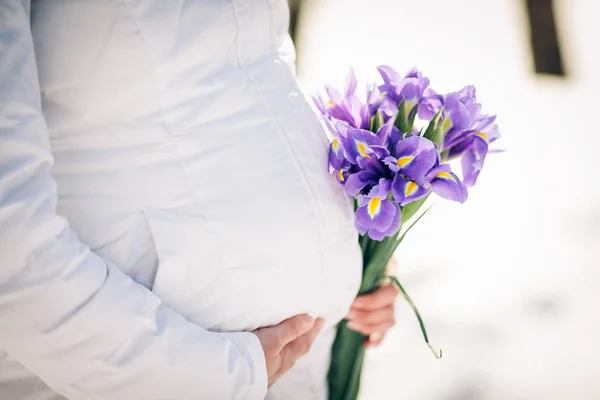 A pregnant mother with flowers holding her belly — Stock Photo, Image