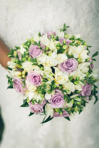 A menyasszony kezében egy csokor gyönyörű lila és fehér virágok — Stock Fotó