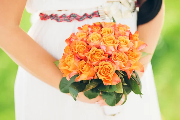 Uma noiva segurando um lindo buquê de rosas laranja — Fotografia de Stock