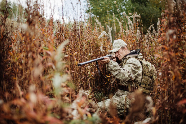 мужчина с дробовиком в лесу
