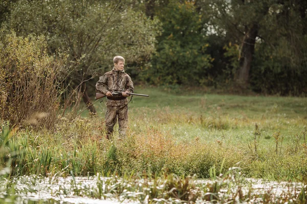 Охотник в камуфляжной одежде готов охотиться с охотничьей винтовкой — стоковое фото