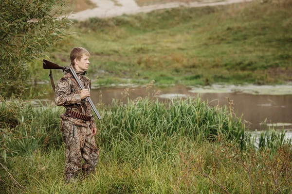 Hunter em roupas de camuflagem pronto para caçar com espingarda de caça — Fotografia de Stock