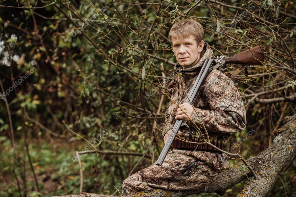 Hunter en ropa de camuflaje listo para cazar con rifle de caza