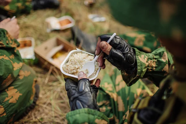 Equipo de soldados se calienta la comida en el fuego y comer en el bosque — Foto de Stock