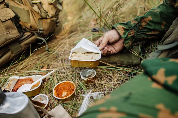 Equipo de soldados se calienta la comida en el fuego y comer en el bosque —  Fotos de Stock