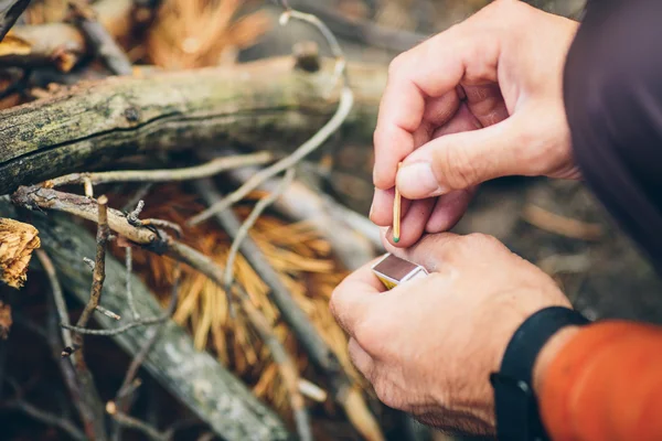 Tourist kindles a fire in summer wood — Stock Photo, Image