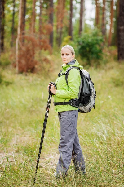 Mujer con equipo de senderismo caminando en el bosque — Foto de Stock