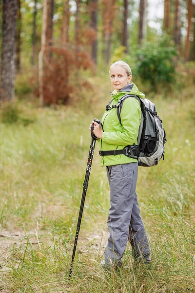 Mujer con equipo de senderismo caminando en el bosque — Foto de Stock