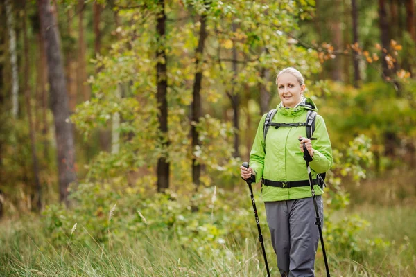 Mujer con equipo de senderismo caminando en el bosque — Foto de Stock