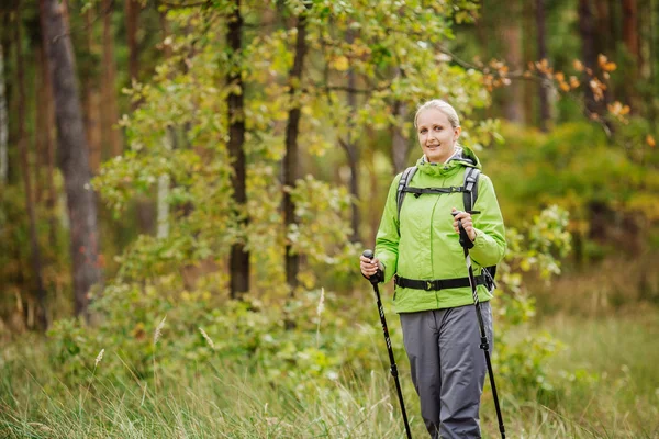 Mujer con equipo de senderismo caminando en el bosque — Foto de Stock