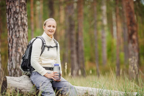 Mujer joven bebiendo agua con mochila en el valle del bosque — Foto de Stock