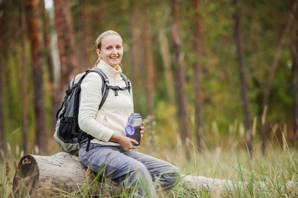Mujer joven bebiendo agua con mochila en el valle del bosque — Foto de Stock