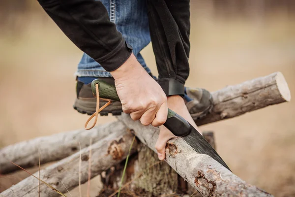 Yang-Mann sägt mit der Handsäge ein Holz — Stockfoto