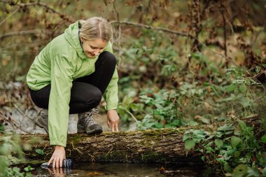 Orman bahar gezisi hiking üzerinde su alarak kadın
