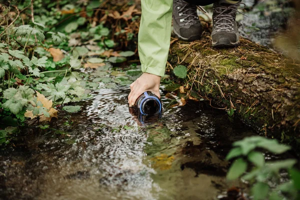 Donna che prende l'acqua dalla sorgente della foresta in escursione — Foto Stock