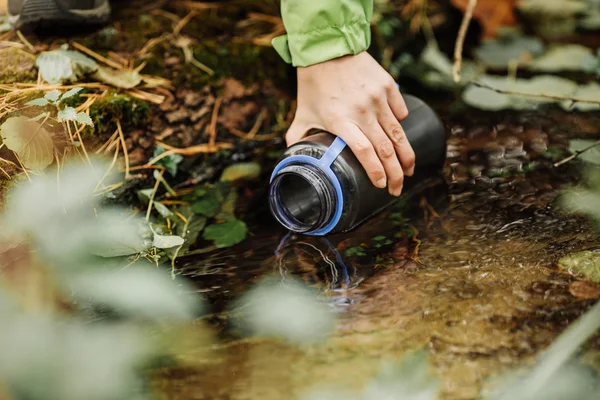 Mujer tomando agua de la primavera del bosque en viaje de senderismo —  Fotos de Stock