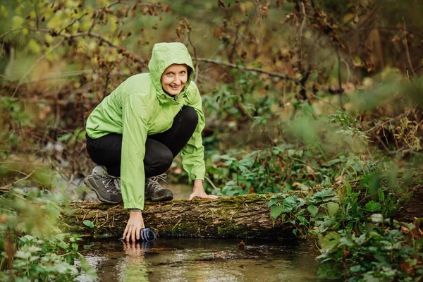 Kvinnan tar vatten från skogen våren på fotvandring resa — Stockfoto