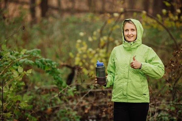 Donna che prende l'acqua dalla sorgente della foresta in escursione mostrando gio — Foto Stock