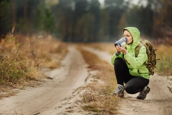 Mujer joven bebiendo agua con mochila en el valle del bosque — Foto de Stock