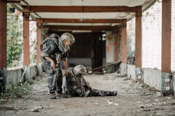 Woman medic soldiers evacuate the injured fellow in arms in the — Stock Photo, Image