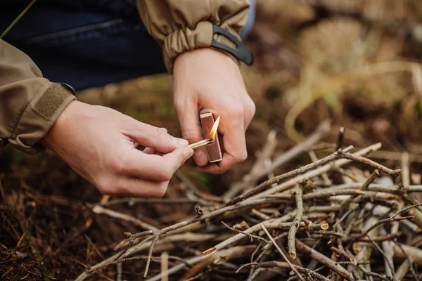 Joven enciende un fuego en madera de verano —  Fotos de Stock