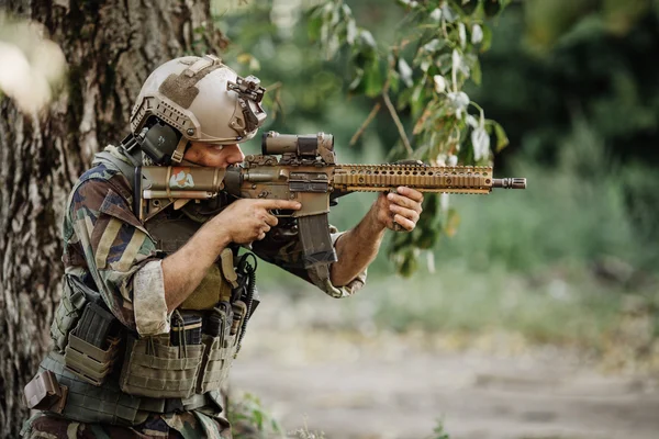 Soldado apontando seu rifle no fundo do campo de batalha — Fotografia de Stock