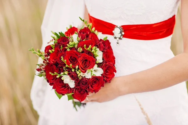 Noiva segurando seu buquê de casamento vermelho de flores — Fotografia de Stock