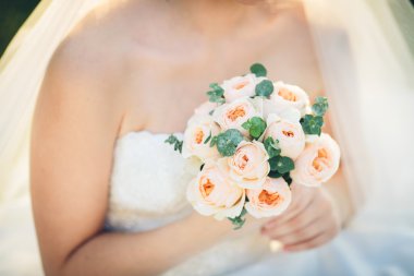 Gelin elinde güllerle düğün buketi tutuyor