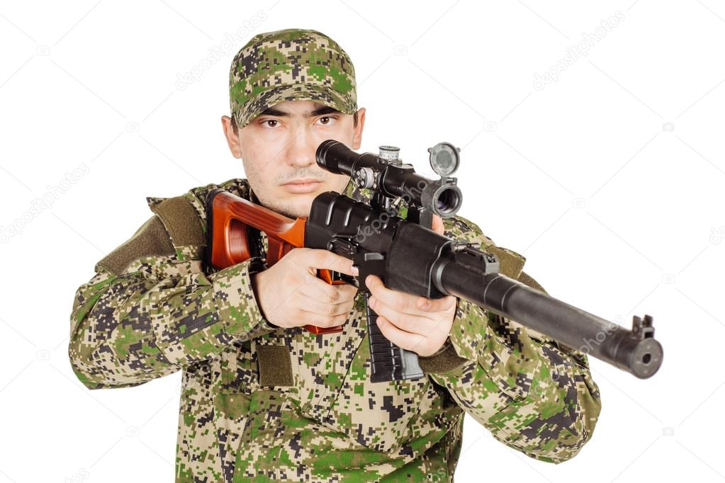 Operador das forças de operações especiais russas com rifle de assalto  kalashnikov, mochila militar e capacete de combate, disparando uma arma no  deserto da síria. ruínas antigas e helicópteros
