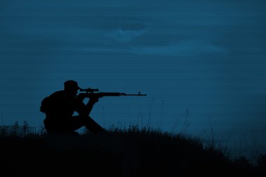 Geceleri keskin nişancı tüfeği ile askeri keskin nişancı silueti. Atış, 