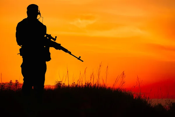Σιλουέτα του στρατιωτικού σκοπευτή με τουφέκι ελεύθερου σκοπευτή στο ηλιοβασίλεμα. Πυροβολισμό, — Φωτογραφία Αρχείου