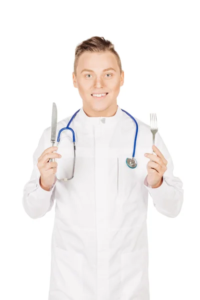Medical doctor in white coat with stethoscope holding a fork and — Zdjęcie stockowe