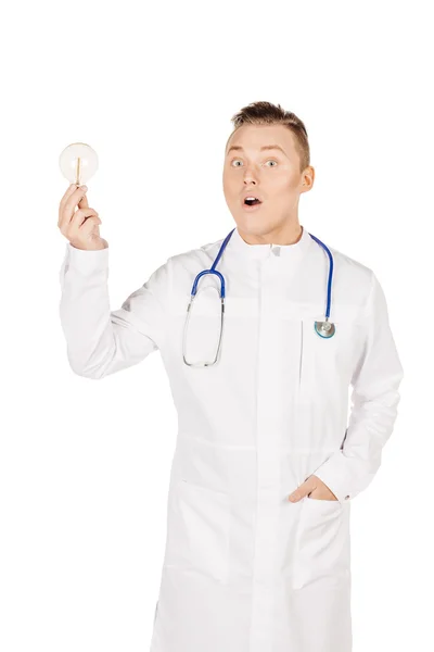 Young male doctor in white coat and stethoscope holding light bu — 스톡 사진