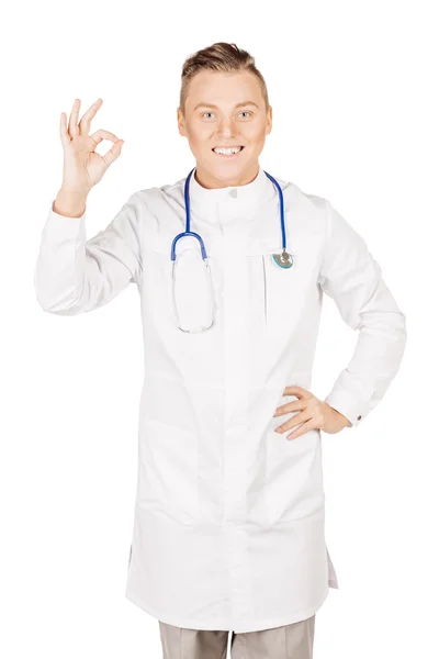 Young male doctor in white coat and stethoscope showing ok hand — Stock Photo, Image