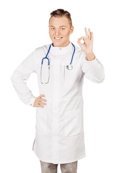 Young male doctor in white coat and stethoscope showing ok hand — Stock Photo, Image